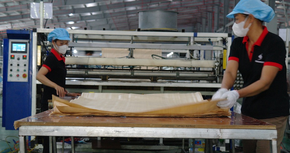 Workers handling fabric at cutting equipment
