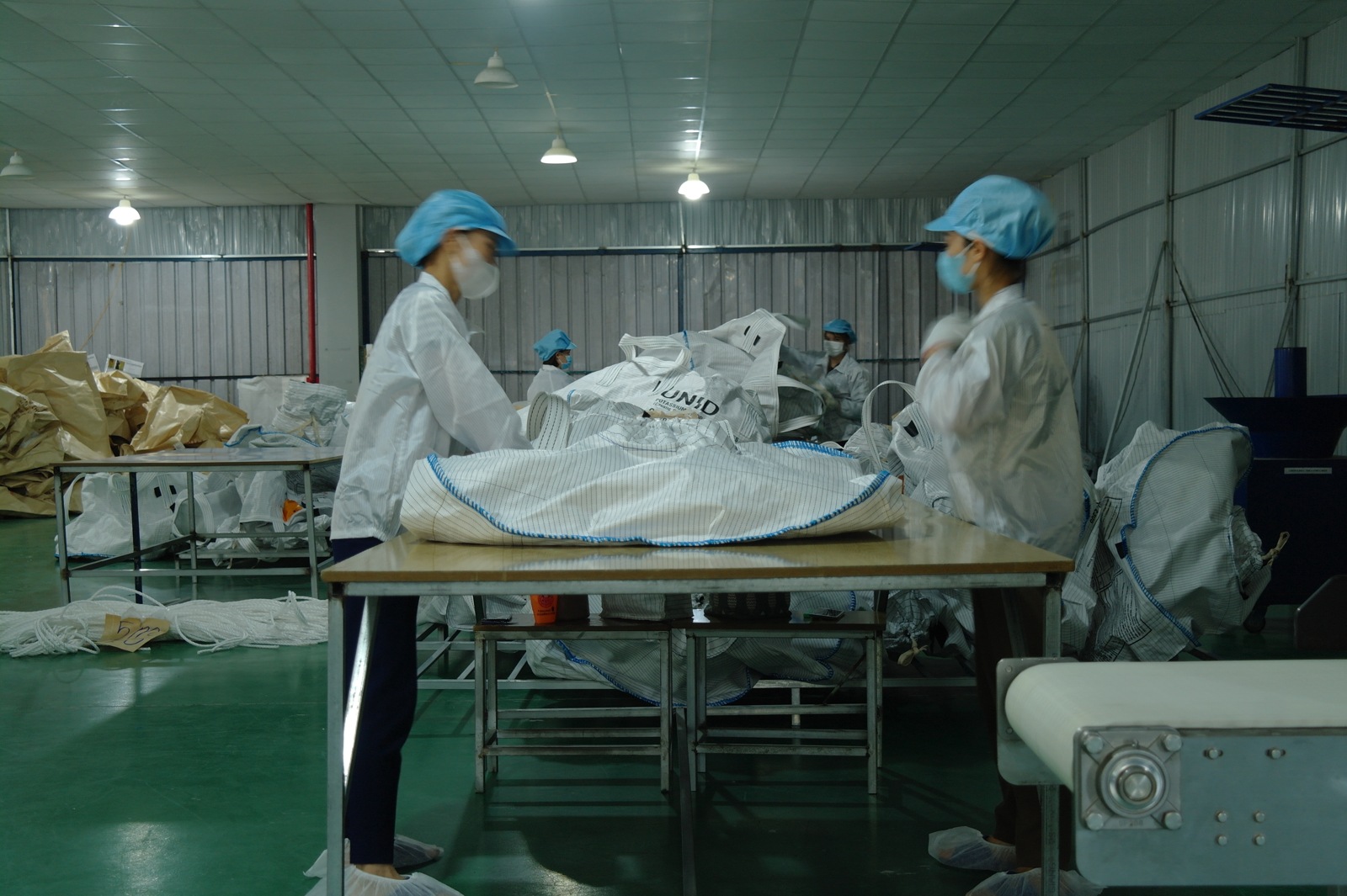 Workers inspecting bag construction at a worktable