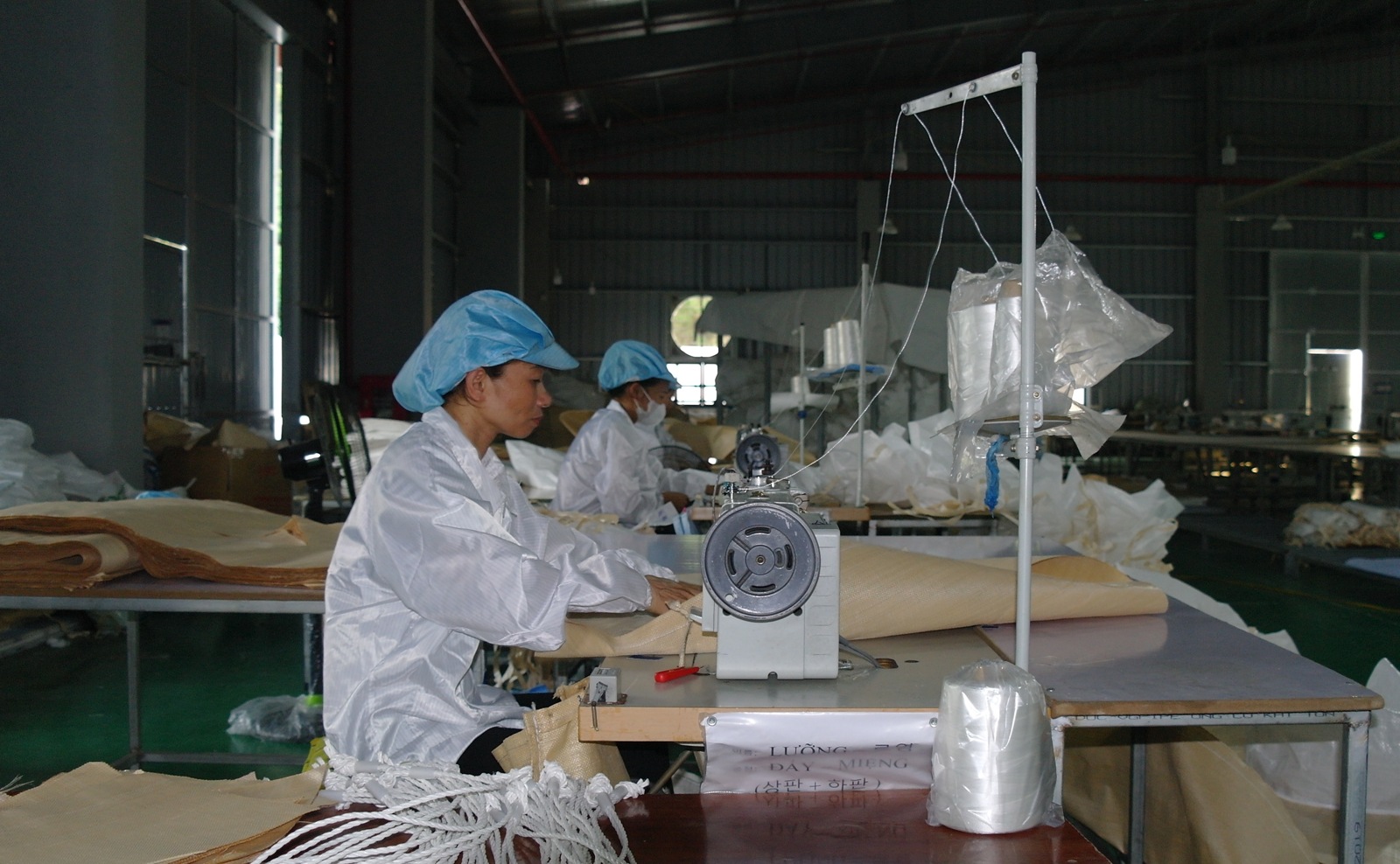 Worker sewing fabric at an industrial sewing machine